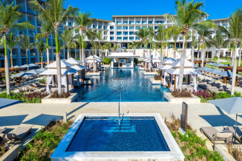Infinity pool with cabanas, lounge chairs, and palm trees creating a luxury all-inclusive resort experience Infinity pool with cabanas, lounge chairs, and palm trees creating a luxury all-inclusive resort experience
