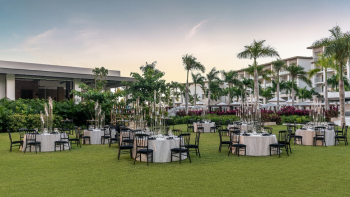 Outdoor wedding reception on lawn with round tables, elegant décor, and tropical landscaping Outdoor wedding reception on lawn with round tables, elegant décor, and tropical landscaping