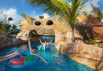 Guests floating in lazy river at Royalton Bavaro Punta Cana with tropical rock features and waterfalls Guests floating in lazy river at Royalton Bavaro Punta Cana with tropical rock features and waterfalls