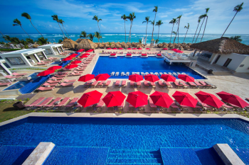 Beachfront pool with red umbrellas, palm trees, and ocean view in Punta Cana Dominican Republic Beachfront pool with red umbrellas, palm trees, and ocean view in Punta Cana Dominican Republic