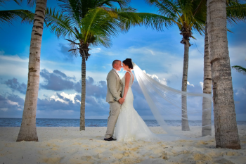 Bride and groom walking on Bavaro Beach in Punta Cana with palm trees and ocean backdrop. Bride and groom walking on Bavaro Beach in Punta Cana with palm trees and ocean backdrop.