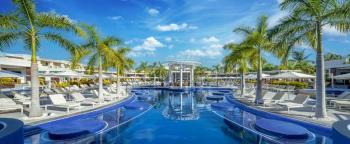 Resort pool with lounge chairs, palm trees, and swim-up areas at Moon Palace The Grand – Cancun.