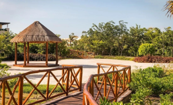 Outdoor garden terrace with wooden bridge and gazebo surrounded by tropical greenery.