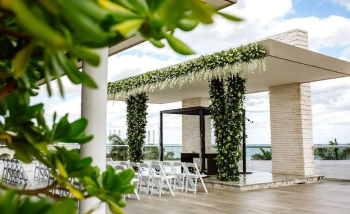 Modern rooftop wedding ceremony setup with floral arch and ocean views
