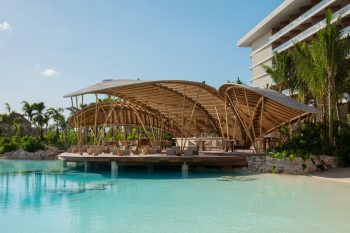 Bamboo restaurant over-water structure at Secrets Moxché with turquoise pool and palm trees