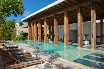 Hydrotherapy pool at the Secrets Moxché spa with lounge chairs and open-air wooden architecture