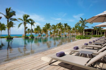 Infinity pool at Secrets Moxché overlooking the Caribbean Sea with palm trees and lounge chairs
