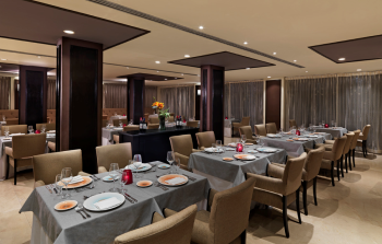 Elegant Italian restaurant dining room with tables set for dinner and soft lighting at Ciao