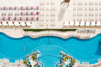 Aerial view of lagoon-style pool with beach loungers and cabanas along the shoreline