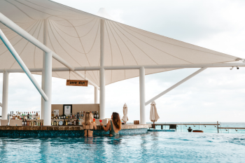 Guests enjoying drinks at a swim-up pool bar with ocean views in Cancun