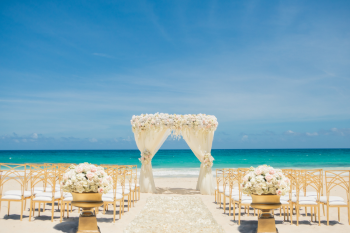 Elegant beach wedding ceremony setup with floral canopy and gold chairs for Lavish Daydream package