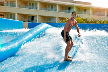 Guest riding the FlowRider surf simulator at Moon Palace Cancun during a destination wedding stay in Mexico. Guest riding the FlowRider surf simulator at Moon Palace Cancun during a destination wedding stay in Mexico.