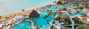 Sunset aerial view of oceanfront pools, palm-lined walkways, and beachfront resort spaces at the Sunrise section of Moon Palace.