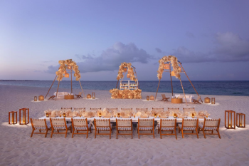 Long beachfront reception table with pampas grass arches and lanterns at Dreams Playa Mujeres at sunset