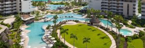 Aerial view of Dreams Playa Mujeres resort with pools, palm-lined lawn, and Caribbean beach in the background